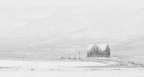 Building on snow covered field against sky