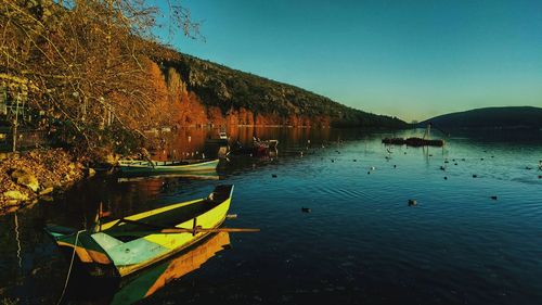 Boats moored in lake against clear sky