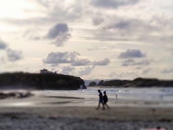 People on beach against sky during sunset