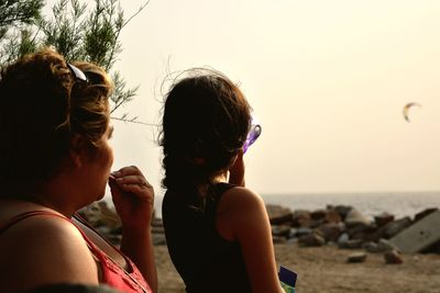 Close-up of siblings at beach against clear sky