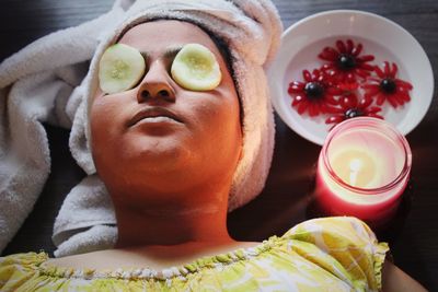 High angle view of woman with facial mask and cucumber slices