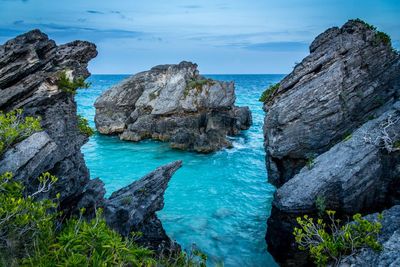 Rock formations by sea against blue sky