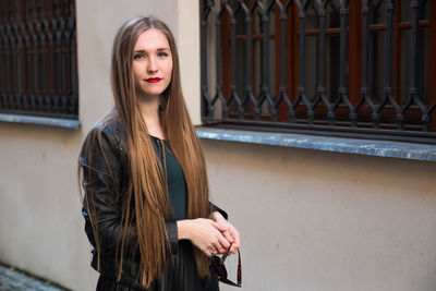 Portrait of beautiful woman standing by wall