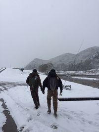 Rear view of people walking on mountain during winter