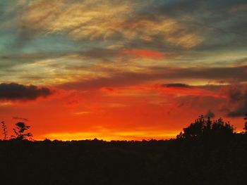 Silhouette landscape against dramatic sky during sunset