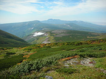 Scenic view of green landscape and mountains against sky