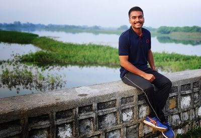 Portrait of young man sitting by lake