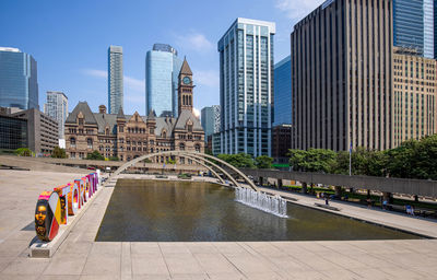 Bridge over river amidst buildings in city against sky