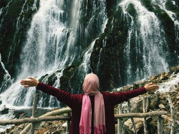 Rear view of man standing against waterfall