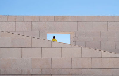 Low angle view of man using mobile phone on built structure