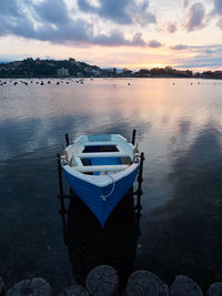 Sailboats moored in lake against sky during sunset