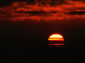Silhouette landscape against dramatic sky during sunset