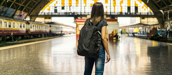 Rear view of woman standing at railroad station