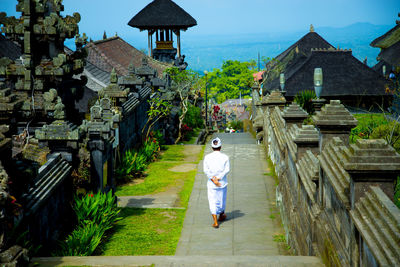 Rear view of woman walking by building against temple