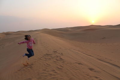 Girl jumping on dunes at dubai's desert