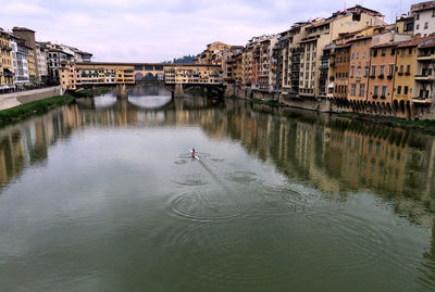 Arch bridge over canal by buildings in city