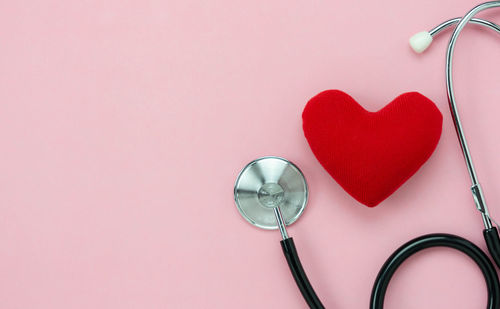 High angle view of heart shape decoration on glass against pink background