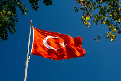 Low angle view of flag against clear blue sky