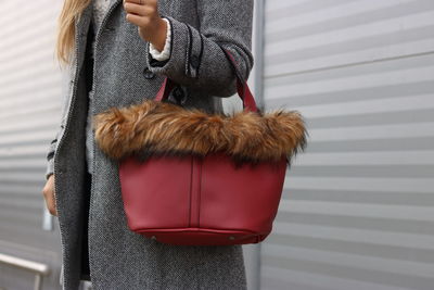 Midsection of woman holding bag while standing indoors