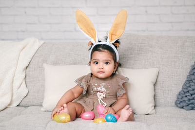 High angle view of cute baby girl sitting on sofa at home