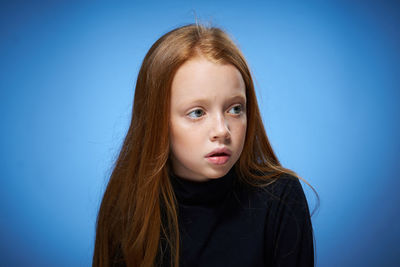 Portrait of young woman against blue background