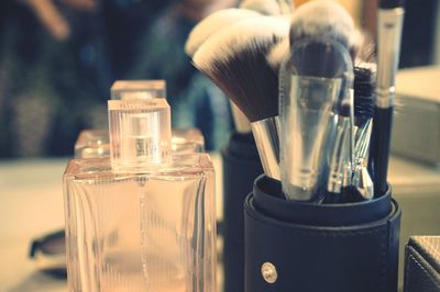 Close-up of make-up brushes by perfume bottle on table