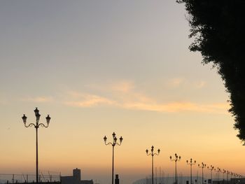 Low angle view of street lights against sky at sunset