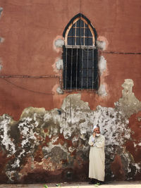 Full length of woman standing against building