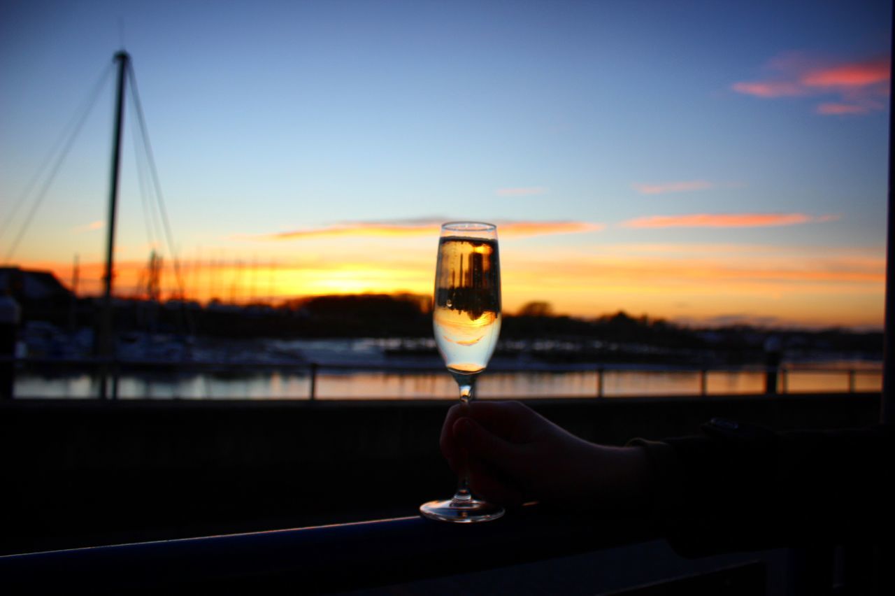 drink, sunset, alcohol, refreshment, sky, food and drink, glass, hand, water, human hand, holding, one person, nature, wine, focus on foreground, human body part, glass - material, real people, close-up, outdoors, drinking, finger