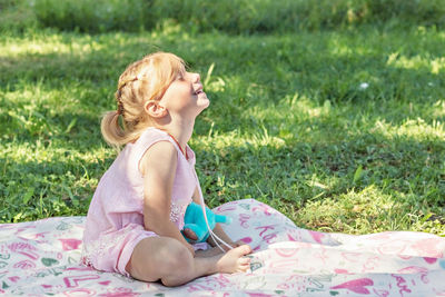 Full length of smiling girl sitting on grass at park