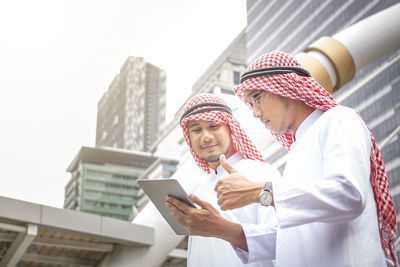 Low angle view of man standing on mobile phone in city