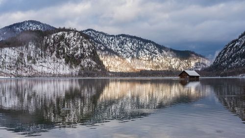 Scenic view of lake by snowcapped mountains against sky