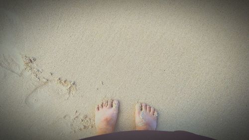 Low section of woman standing on sand at beach