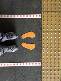 Low section of man standing by foot sign on station