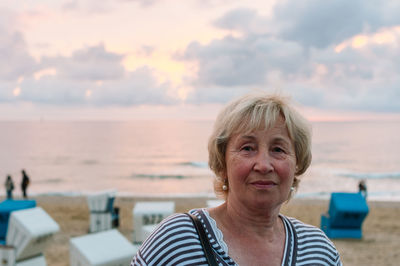 Portrait of woman standing at beach against sky