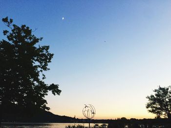 Silhouette trees against clear sky at sunset