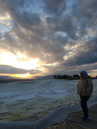 Rear view of woman standing on beach during sunset