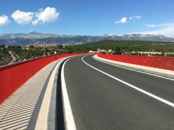 Empty road leading towards mountain against sky