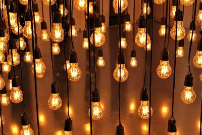 Full frame shot of illuminated light bulbs hanging at night