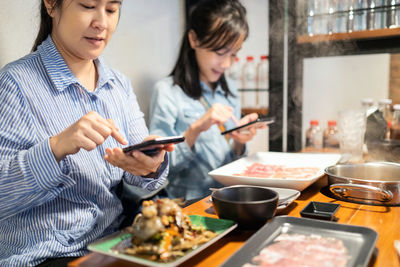 Midsection of woman holding ice cream on table