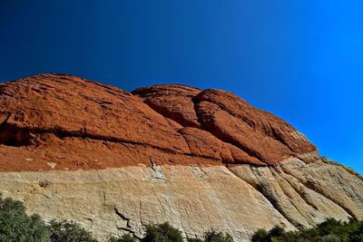 Low angle view of rocky mountain against blue sky