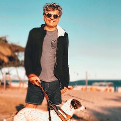 Young man wearing sunglasses at beach against sky