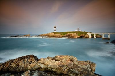 Lighthouse by sea against sky