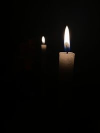 Close-up of lit candle in darkroom