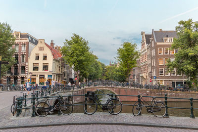 Bicycle parked by railing against buildings in city