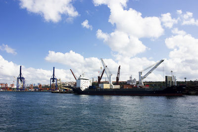 Cranes at commercial dock against sky