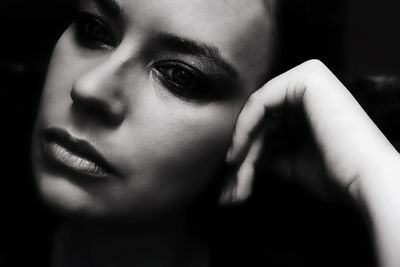 Close-up of thoughtful woman with make-up looking away in darkroom