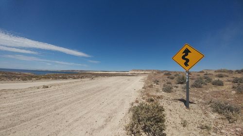 Road sign in desert against blue sky