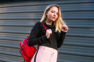 Young blond hair woman carrying a backpack. blond hair girl walking on the street with backpack.