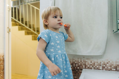 Portrait of cute girl blowing bubbles while standing against wall